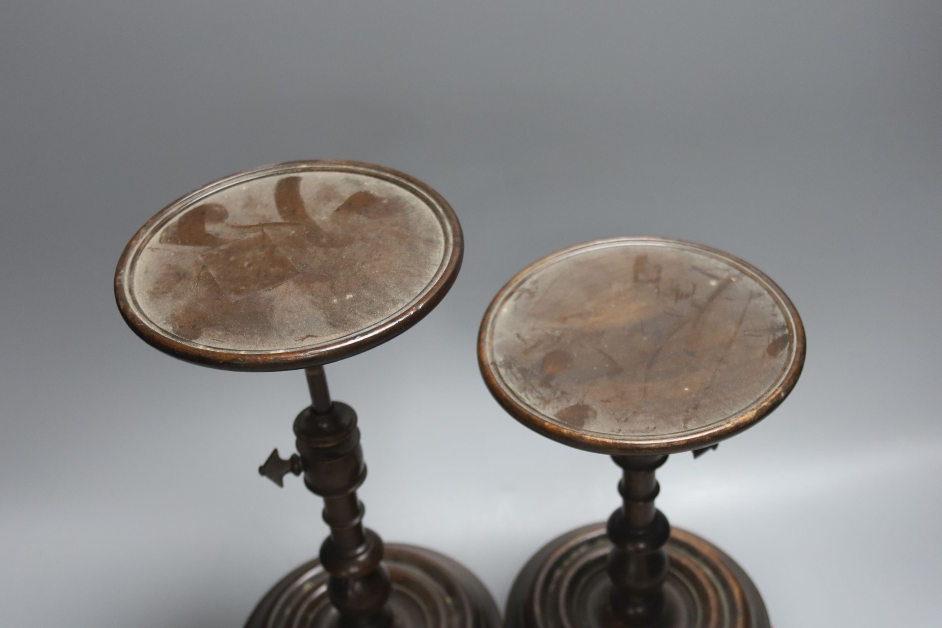A pair of Georgian style stained beech adjustable candle stands, height 24cm